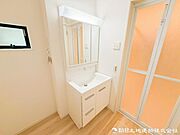 【洗面化粧台】 三面鏡裏収納付き洗面化粧台。身支度用品をすっきり収納でき、脱衣スペースも広く確保された快適な洗面空間です。