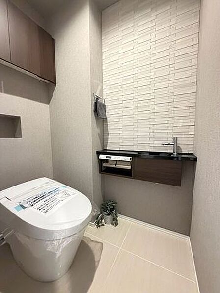カウンターと上部収納を備えた清潔感あふれる温水洗浄便座付きトイレ!アクセントクロスが洗練された空間を演出し、毎日の生活の中でホッと一息つける快適なプライベート空間に仕上がっています♪