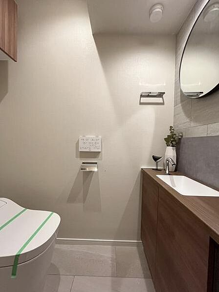 トイレ　丸い鏡のある手洗い。清潔感あるトイレスペースです。