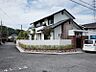 外観：周辺の緑と調和した、落ち着いた雰囲気の邸宅。レンガ調のアクセントウォールが、洗練された外観を演出しています。お車も駐車可能で、快適な毎日をサポートします。