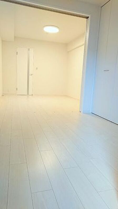 白を基調としたフローリングと壁紙で統一された室内には、引き戸で仕切れる隣接した部屋や作り付けのクローゼットを備えており、奥のドアにはスリットガラスがあしらわれています。