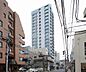 外観：白とグレーの色合いを基調とした直線的なフォルムが特徴的な高層マンションで、規則的に配置された窓やバルコニー、上層階のガラス張りデザインが目を引くスタイリッシュな外観となっています。