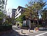 外観：ブラウンやグレーを基調とした落ち着いた色合いの外観で、敷地周りには緑豊かな植栽が配置されており、歩道から敷地内へと続くアプローチ部分には整然と車止めやベンチが設置されています。