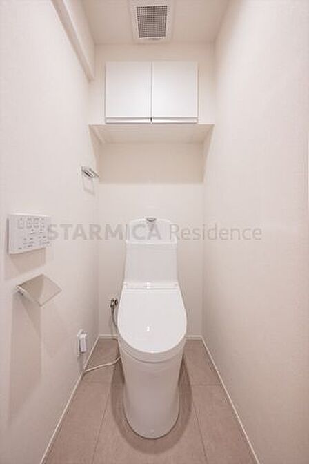 パワー脱臭機能などを備えた温水洗浄便座付きトイレ。吊戸棚にトイレットペーパーやお掃除道具などもスッキリ収納可能です。