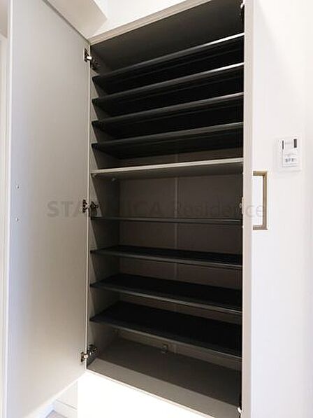 大容量の下足収納を備え、足元から明るい照明が照らす玄関