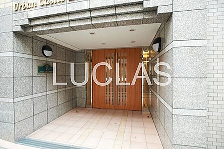 グレーのタイル張りと木目調ドアが調和したエントランス。都市の生活にふさわしい落ち着いた佇まいです。