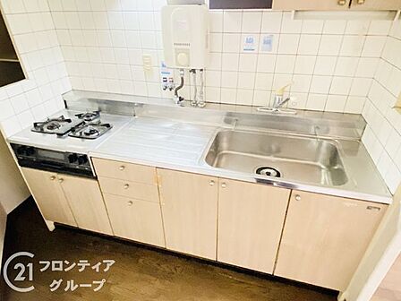 木目調のパネルが温かみを添えるキッチンは、毎日の料理を楽しく演出してくれます。機能的な三口コンロと充分な作業スペースが確保されており、効率よく家事をこなしながら家族との時間も大切にできます