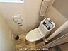 トイレ：清潔感のある白い便器と、温かみのある木目調のフロアが調和したトイレ空間。小窓からの採光も心地よく、快適にお過ごしいただけます。
