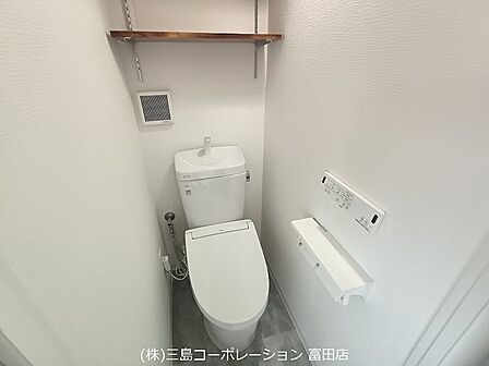 清潔感のある白い壁とウォシュレット付きトイレで、毎日を快適に。壁には便利な棚と換気扇も設置されており、使いやすさに配慮しています。