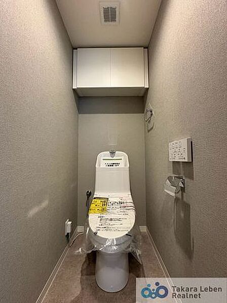 ウォシュレット機能付きのトイレは壁掛けリモコンの上位グレードを採用。便座がスッキリした印象となり、限られた空間を広く見せる効果があります。