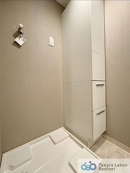 洗濯機置場。収納棚が設置されている為、洗剤類の収納場所としてお使いいただけます。