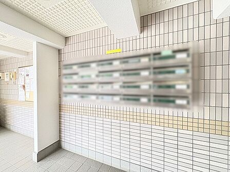 タイル貼りの壁面が整然と並ぶ、清潔感と落ち着きのある共用エントランス空間