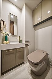 タンクの見えないすっきりとした印象のトイレ。鏡付きの手洗い場は、身だしなみチェックにも役立ちます。2ヶ所に収納スペースがあり、トイレットペーパーや掃除用具を隠しておけます。