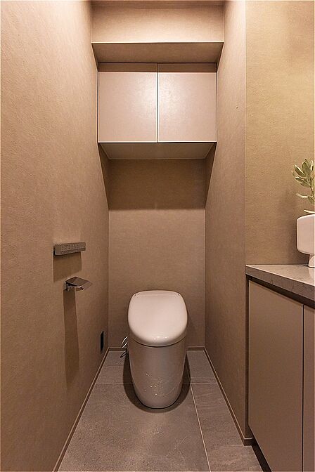 清潔に利用できる温水洗浄機能付きトイレです。上部には収納棚を設置しています。トイレットペーパーや掃除用品を収納することができます。
