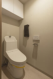 【トイレ】毎日清潔に使用できる、温水洗浄便座を設置しています。壁にリモコンがあるので、操作がしやすいです。吊戸棚にはトイレットペーパーなどを収納可能。