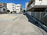 外観：広々とした空間に、新たに整備された区画が並びます。隣接する建物が生活利便性の高さを感じさせ、新しい暮らしの舞台となる予感に満ちています。