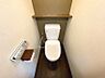 トイレ：落ち着いた色調で統一されたトイレ空間。温水洗浄機能付きで、壁には棚も備え付けられています。