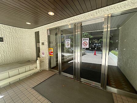 開放的なガラス扉のエントランスが、訪れる人を明るく迎えます。セキュリティ対策も安心感を高めます。