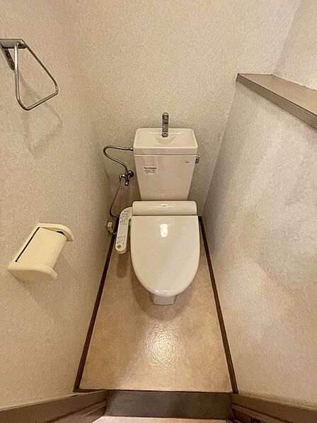 温水洗浄便座を設置したトイレです。トイレットペーパーホルダーやタオル掛けも備え付けられています。日々の暮らしを快適にする設備です。