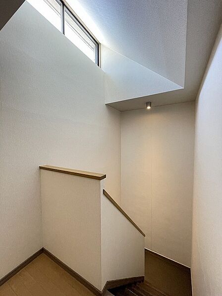 採光窓から自然光が差し込み、明るい空間を演出する階段。壁面と手すりのコントラストが美しい、洗練されたデザインです。