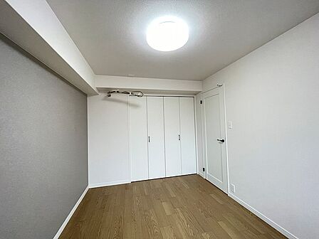 木目調フローリングとアクセントクロスが落ち着いた雰囲気を醸し出す洋室。収納も完備されており、居心地の良いプライベート空間を演出します。