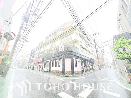 通りに面した、白を基調としたマンションです。1階には飲食店が入っており、にぎやかな雰囲気を醸し出しています。