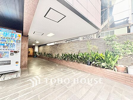 通りから一歩入ったアプローチには丁寧に手入れされた植栽が並び、住まい手や訪れる人を心地よく迎えてくれます。自動販売機も設置されており、日常のちょっとした便利さも嬉しいポイントです。