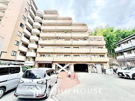 透明感あるガラスバルコニーが光を美しく反射するスタイリッシュなファサード。足元には色鮮やかな花や生垣などの豊富な植栽が彩りを添え、堂々としたスケール感と華やかさを放ちます。