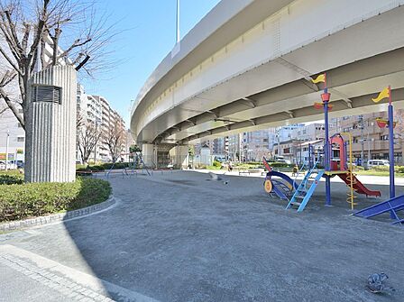 高速道路のランプが日陰の役割も果たしてくれる顔の形のマンホールベンチがある公園。