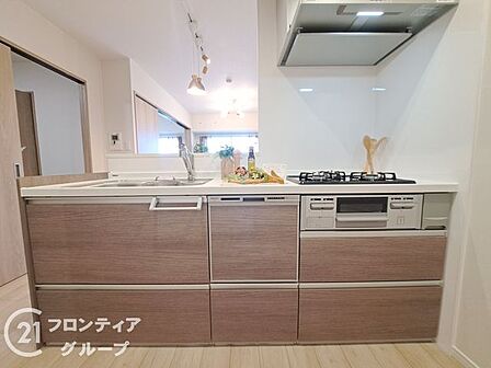 木目調のパネルが温かみを添える、上質で機能的なシステムキッチンです。リビングを見渡せる開放的な設計により、家族との会話を楽しみながら快適にお料理ができる贅沢な空間に仕上がっています