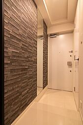 重厚感のある石調アクセントウォールが印象的な玄関。シューズインクローゼットを備え、落ち着いた雰囲気で住まいの第一印象を上質に演出します。現地（2025年11月）撮影