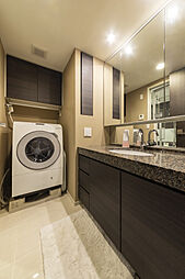 【ホテルライクな意匠】重厚感ある天然石カウンターの洗面台が、朝のひと時を優雅に演出します。三面鏡裏の収納やリネン庫など、機能性も兼備。細部まで美意識が息づく、スカイフォレストレジデンスの洗練された私邸