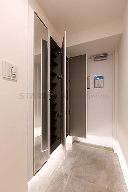 大容量の下足収納を備え、足元から明るい照明が照らす玄関