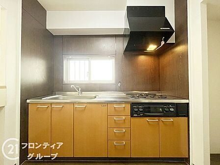 落ち着いた木目調のパネルが印象的なキッチンは、お料理をしながらリビングの様子も見守れる設計です。充実した収納スペースも備わっており、機能美と使い勝手の良さを両立した空間に仕上がっています