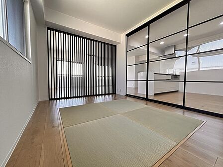 黒の建具が白壁に美しく映える、和洋折衷の洗練された空間です。フラットに繋がる畳のスペースは、客間やお子様の遊び場、お昼寝にも活用できます。