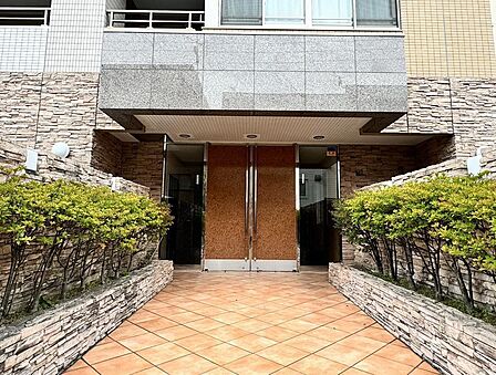 高級感のある石調の壁面とあたたかみのある木目調の扉が調和した、居住者やゲストを心地よく迎え入れる気品漂うエントランスです。