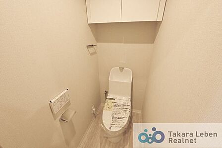 吊戸棚付き温水洗浄機能付きトイレ。リモコンは操作がしやすい壁掛けタイプです。