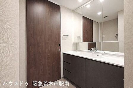 広々とした洗面化粧台。三面鏡と収納も充実しており、朝の身支度も快適に行える使い勝手の良い空間です