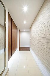 白く清潔感のある廊下と、木目調のドアが落ち着いた雰囲気を醸し出します。 タイルとフローリングの組み合わせが、空間にリズムを生み出します。