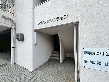 白を基調とした外壁に、立体的な切り文字の建物名が掲示されたエントランスです。