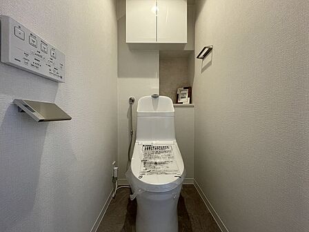 清潔感漂うホワイト調の落ち着いた雰囲気のトイレ空間です！上部にはトイレットペーパーやお掃除用品を収納できる吊戸棚を設置しており、足元をすっきりと保ちながら衛生的にご使用いただけます