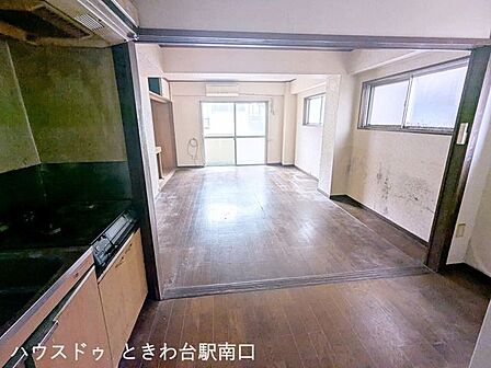 落ち着いた木目調のフロアが広がる居室空間です。大きな窓からは自然光が入り込み、キッチンとのつながりもスムーズな動線が確保されています。