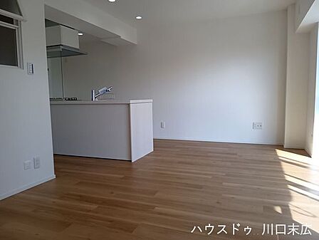 家族の会話が弾む対面式キッチンを備えたリビング空間。木の質感が伝わる床材が、穏やかなリラックスタイムを演出します。
