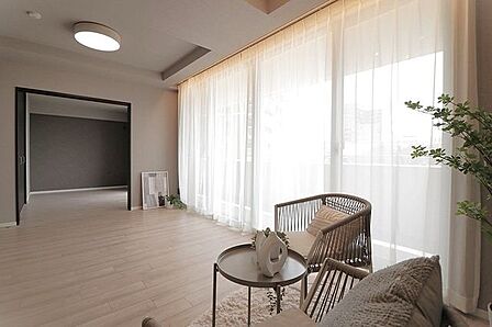 大きな窓から自然光が差し込む広々としたリビングダイニング。隣室との連なりが開放感をもたらします。