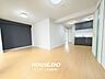 リビング/ダイニング：白を基調とした壁面にシックなダークグレーのアクセントクロスとキッチンが調和するスタイリッシュな室内。ナチュラルカラーのフローリングが空間全体にやわらかな明るさを広げます。