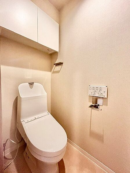 白を基調とした清潔感あふれる温水洗浄便座付きトイレ！上部にはトイレットペーパーや備品をしっかり収納できる棚を備えており、生活感を隠してすっきり保てます。スタイリッシュで快適な空間です。
