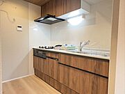 木目調デザインが温もりを添える、落ち着いた色合いのシステムキッチンです。すっきりと壁付けされた配置で、お料理に集中しやすい動線を確保。家族のために毎日使う場所だからこそ、心地よさを大切にしました。