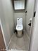 トイレ：清潔感のあるトイレ空間。手洗いタンク付きのトイレに加え、上部には収納棚を備えており、トイレットペーパーなどの収納にも便利です。落ち着いた色合いで、すっきりとした印象に仕上がっています。