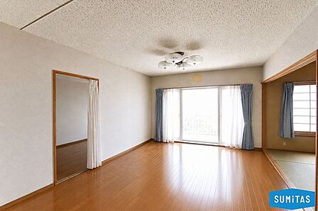大きな窓から明るい光が差し込む、広々としたリビング空間。※現地の撮影写真を基にCG加工編集済