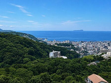 緑の山並みと伊東市街の先に初島浮かぶ海の眺望が広がります